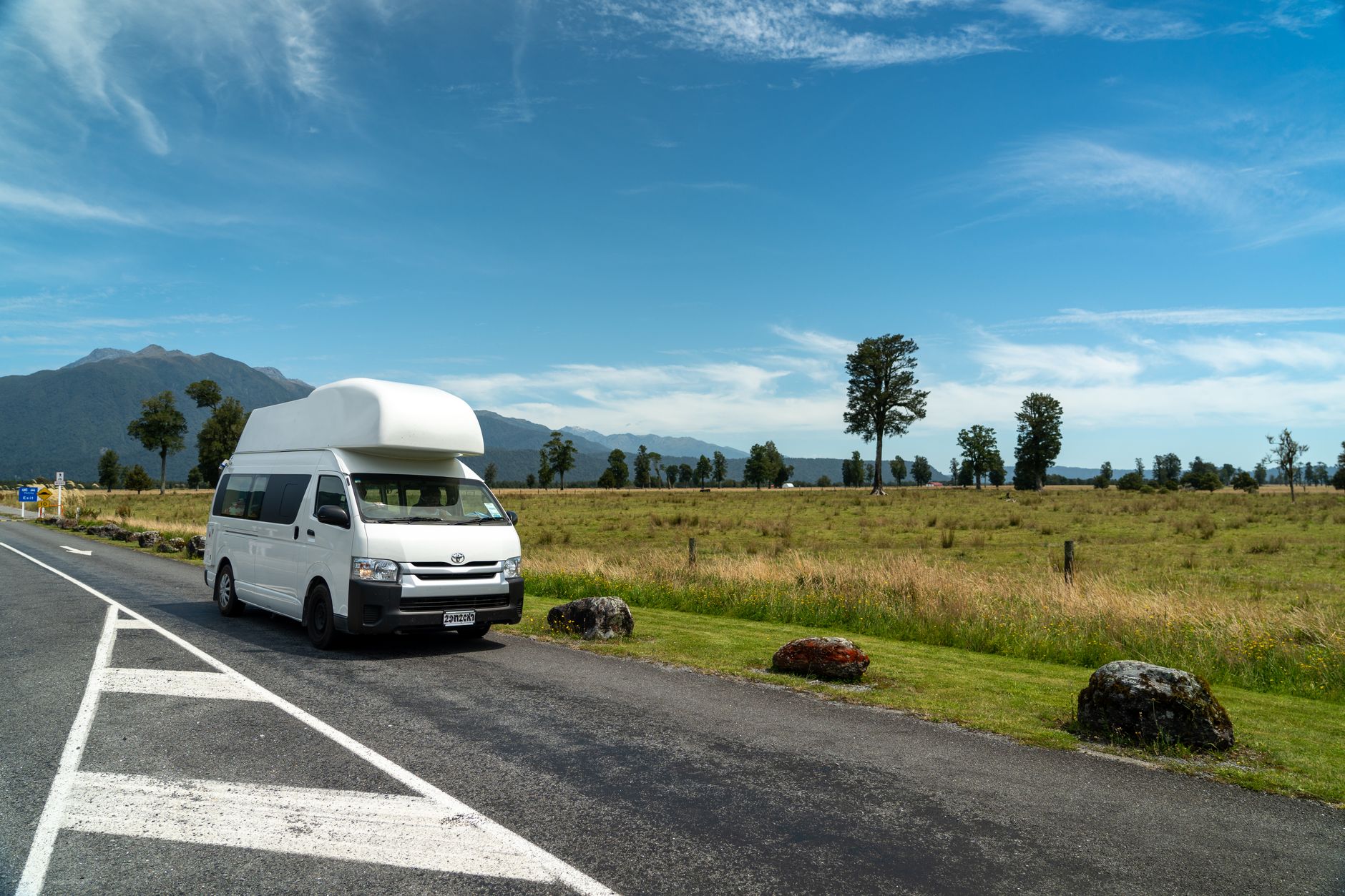 Campervan parked along scenic coastal highway in New Zealand